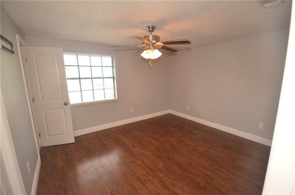 2444 Southeast Washington Street Stuart, FL 34997 - Photo 8 of 13 an empty room with wooden floor fan and windows