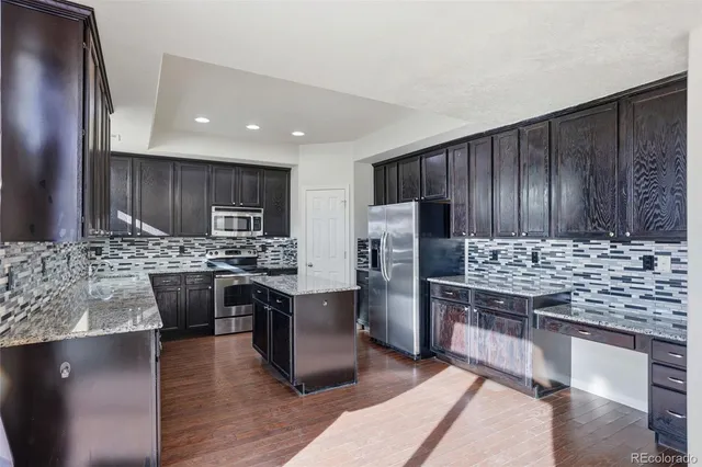 a kitchen with stainless steel appliances kitchen island granite countertop a stove refrigerator sink and cabinets