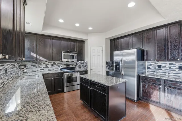 a kitchen with stainless steel appliances granite countertop wooden cabinets a stove top oven a sink and dishwasher