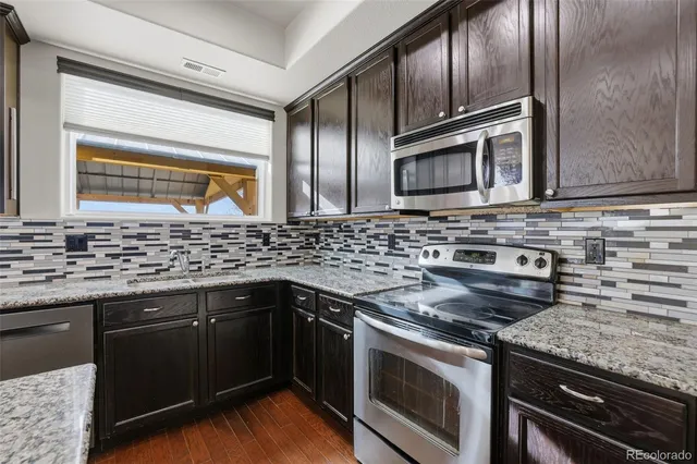 a kitchen with stainless steel appliances granite countertop wooden cabinets and a stove top oven