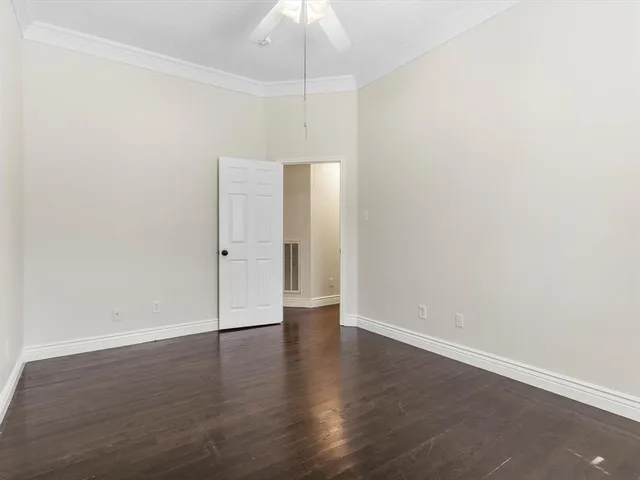 an empty room with wooden floor and chandelier fan