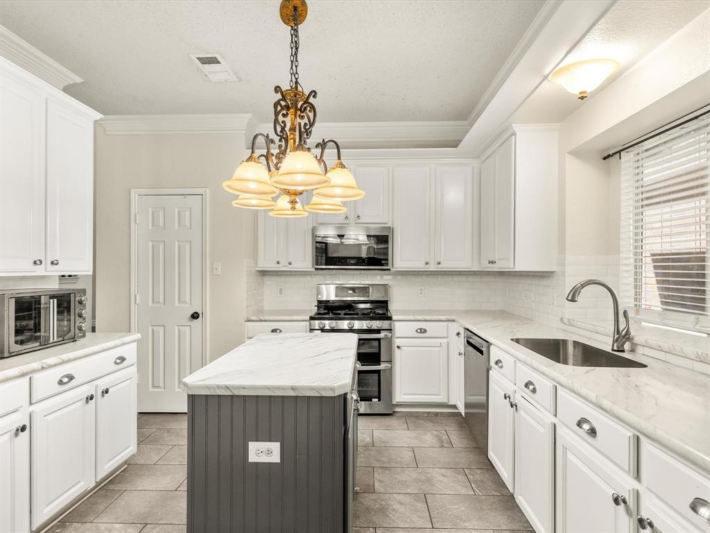 7121 Raintree Way Denton, TX 76210 - Photo 2 of 38 a kitchen with stainless steel appliances a sink stove and refrigerator