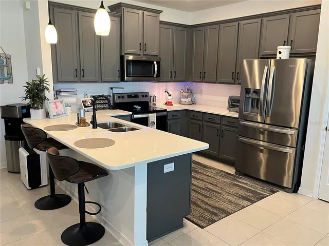 a kitchen with stainless steel appliances a refrigerator a sink a stove a dining table and chairs