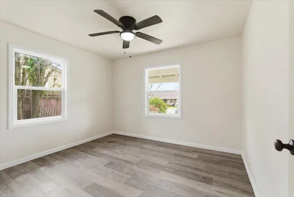 an empty room with wooden floor and windows