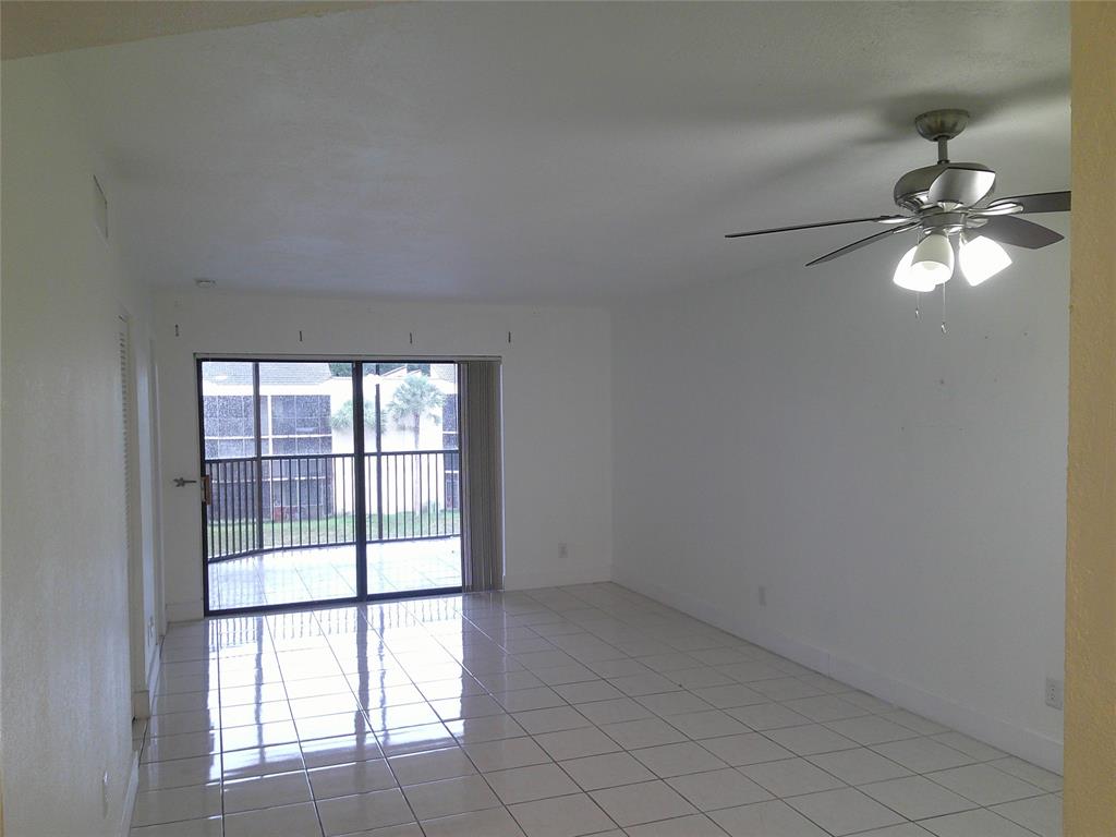 3199 Foxcroft Road, Unit 306 Miramar, FL 33025 - Photo 6 of 12 an empty room with chandelier fan and windows