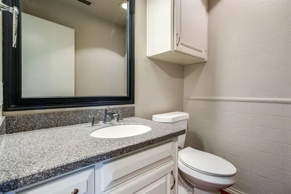 a bathroom with a granite countertop toilet sink and mirror