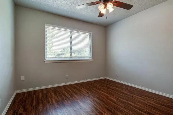 an empty room with a hardwood and ceiling fan