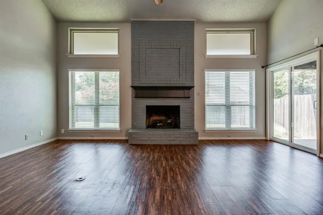 an empty room with wooden floor fireplace and windows
