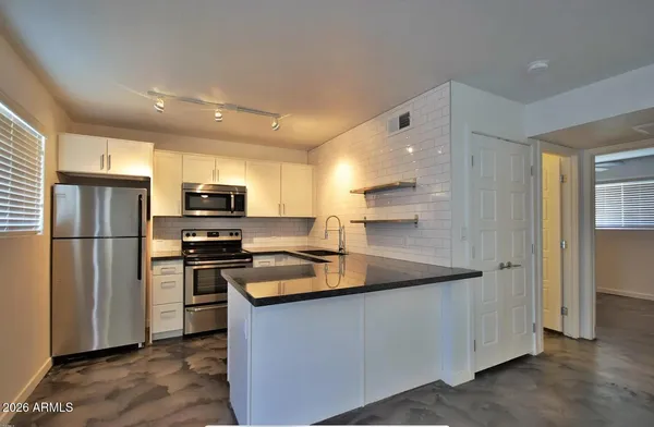 a kitchen with stainless steel appliances granite countertop a refrigerator a stove a sink and a microwave