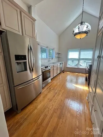 a kitchen with stainless steel appliances granite countertop a refrigerator a stove a sink dishwasher and a refrigerator with wooden floor