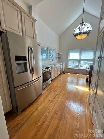 a kitchen with stainless steel appliances granite countertop a refrigerator a stove a sink dishwasher and a refrigerator with wooden floor