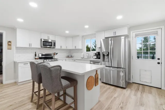 a kitchen with stainless steel appliances a refrigerator stove microwave and white cabinets