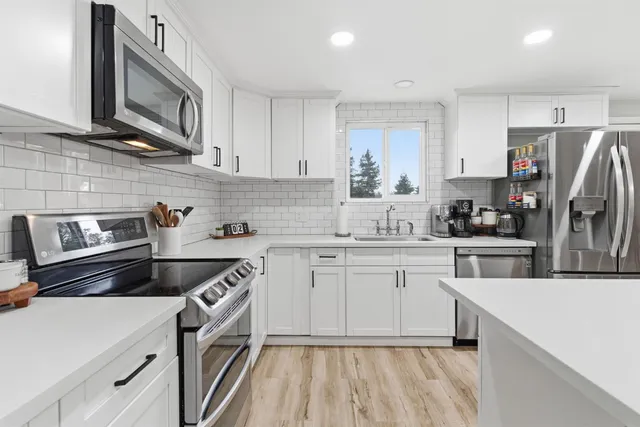 a kitchen with cabinets stainless steel appliances a sink and wooden floor