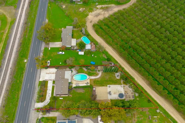 an aerial view of a house with swimming pool and large trees