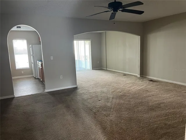 an empty room with a chandelier fan and windows