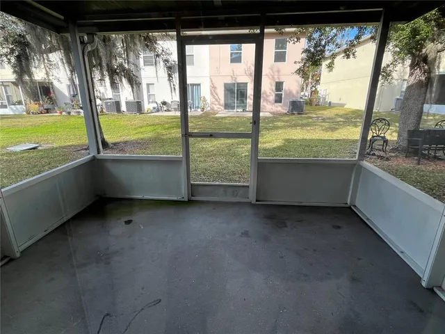 a view of an empty room with a floor to ceiling window next to a yard
