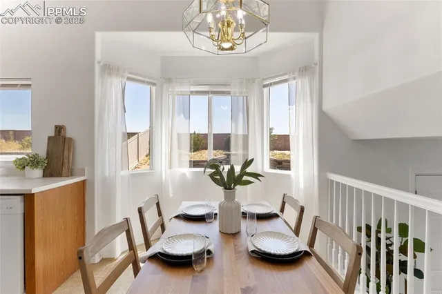 a view of a dining room with furniture a chandelier and windows