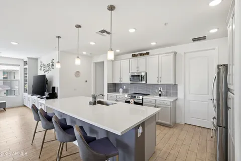 a kitchen with stainless steel appliances a stove a sink a refrigerator a center island a dining table and chairs