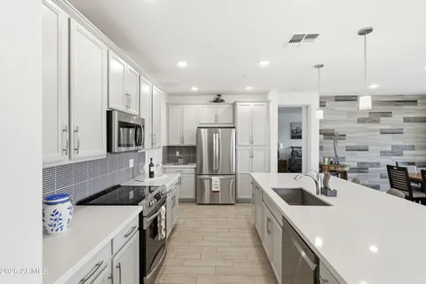 a kitchen that has a lot of cabinets and stainless steel appliances