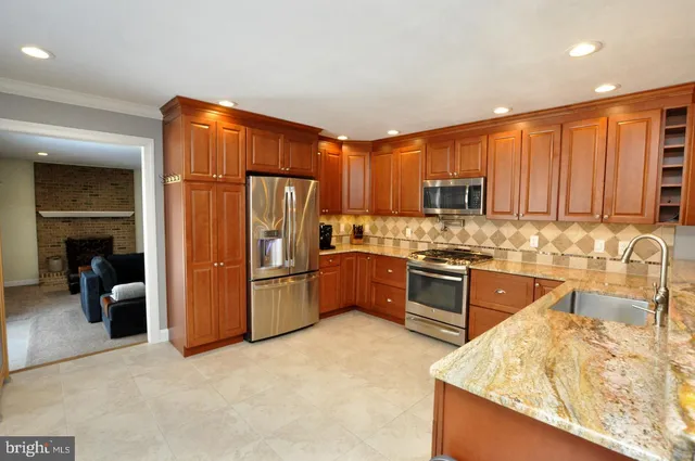 a kitchen with granite countertop a refrigerator and a stove top oven