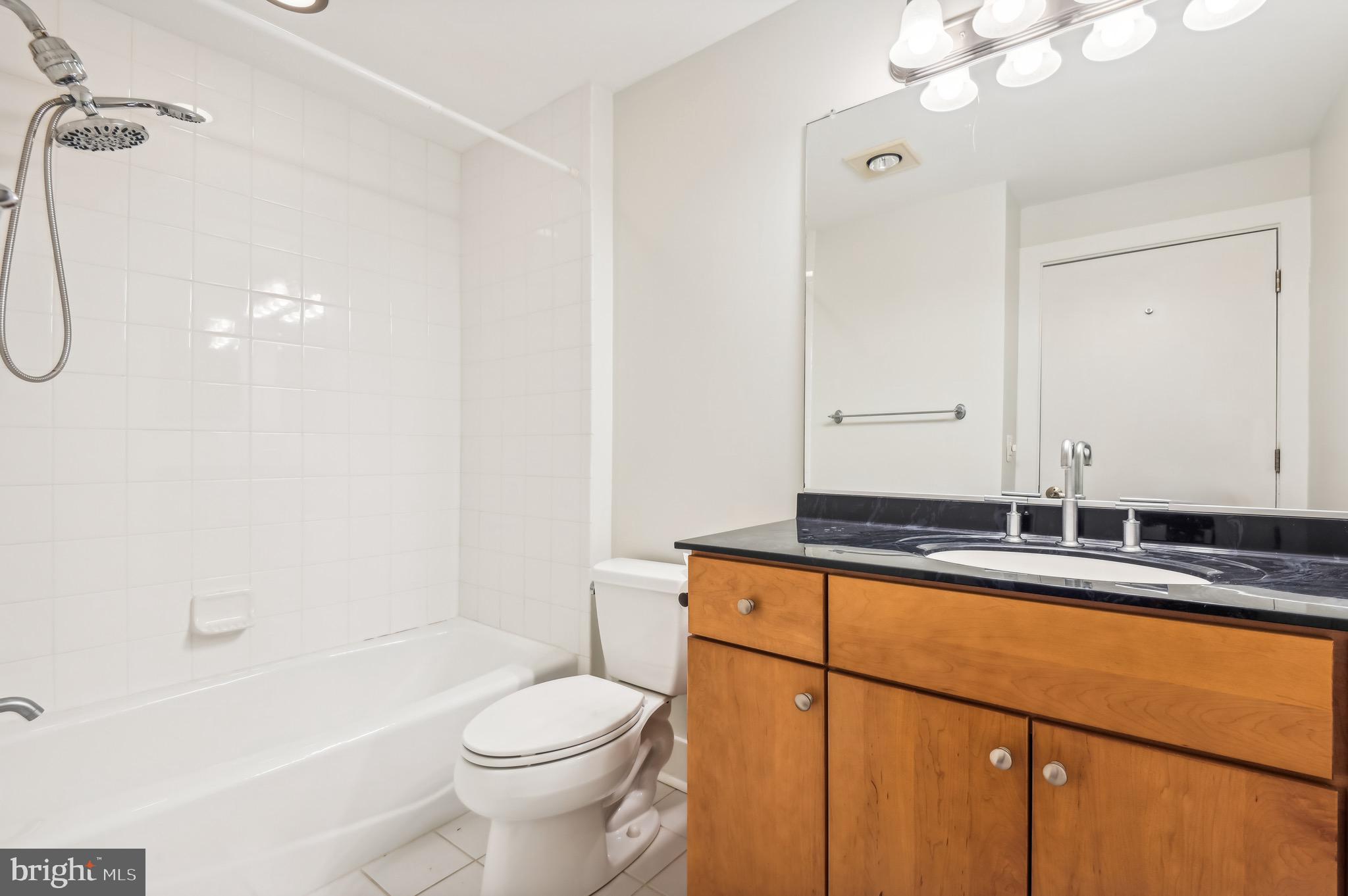 1400 Lancaster Street, Unit 502 Baltimore, MD 21231 - Photo 36 of 48 a bathroom with a granite countertop sink a toilet a mirror and shower