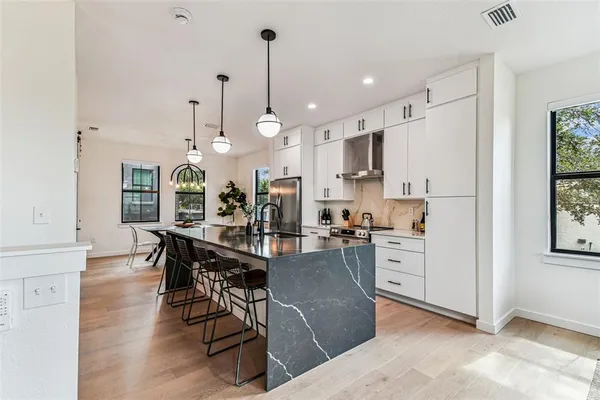 a living room with furniture kitchen view and a wooden floor
