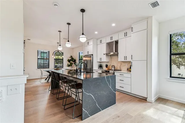a living room with furniture kitchen view and a wooden floor