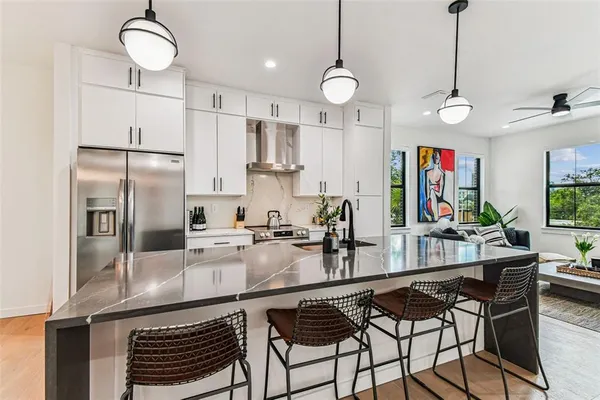 a kitchen with stainless steel appliances granite countertop a stove a refrigerator a kitchen island a sink and a refrigerator