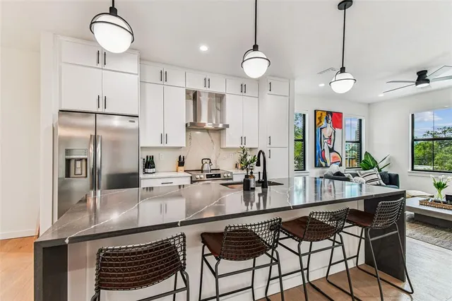 a kitchen with stainless steel appliances granite countertop a stove a refrigerator a kitchen island a sink and a refrigerator