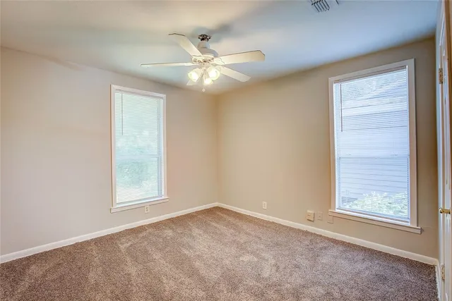 an empty room with windows and fan