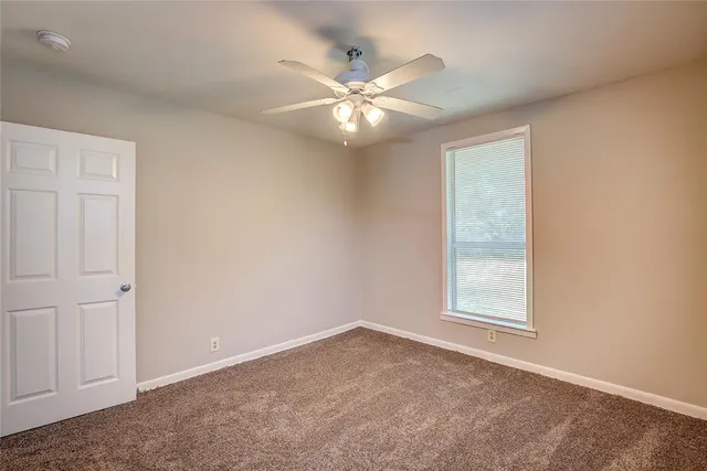 an empty room with a ceiling fan and a window