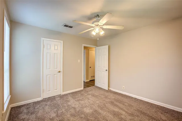an empty room with closet and a chandelier fan