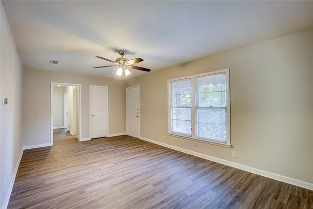 an empty room with wooden floor and windows