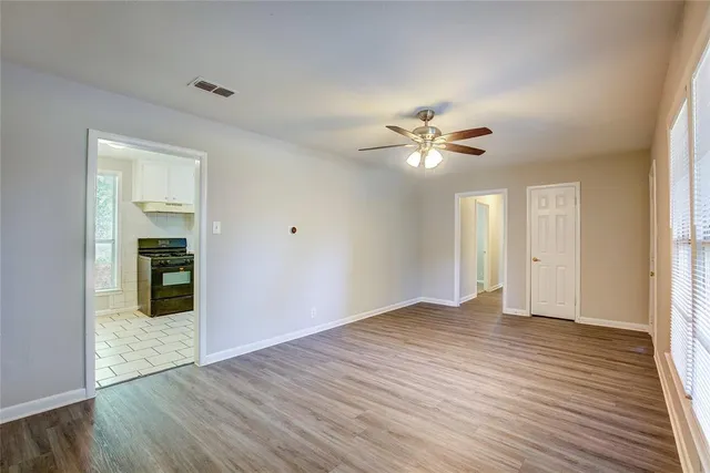 an empty room with wooden floor and a ceiling fan