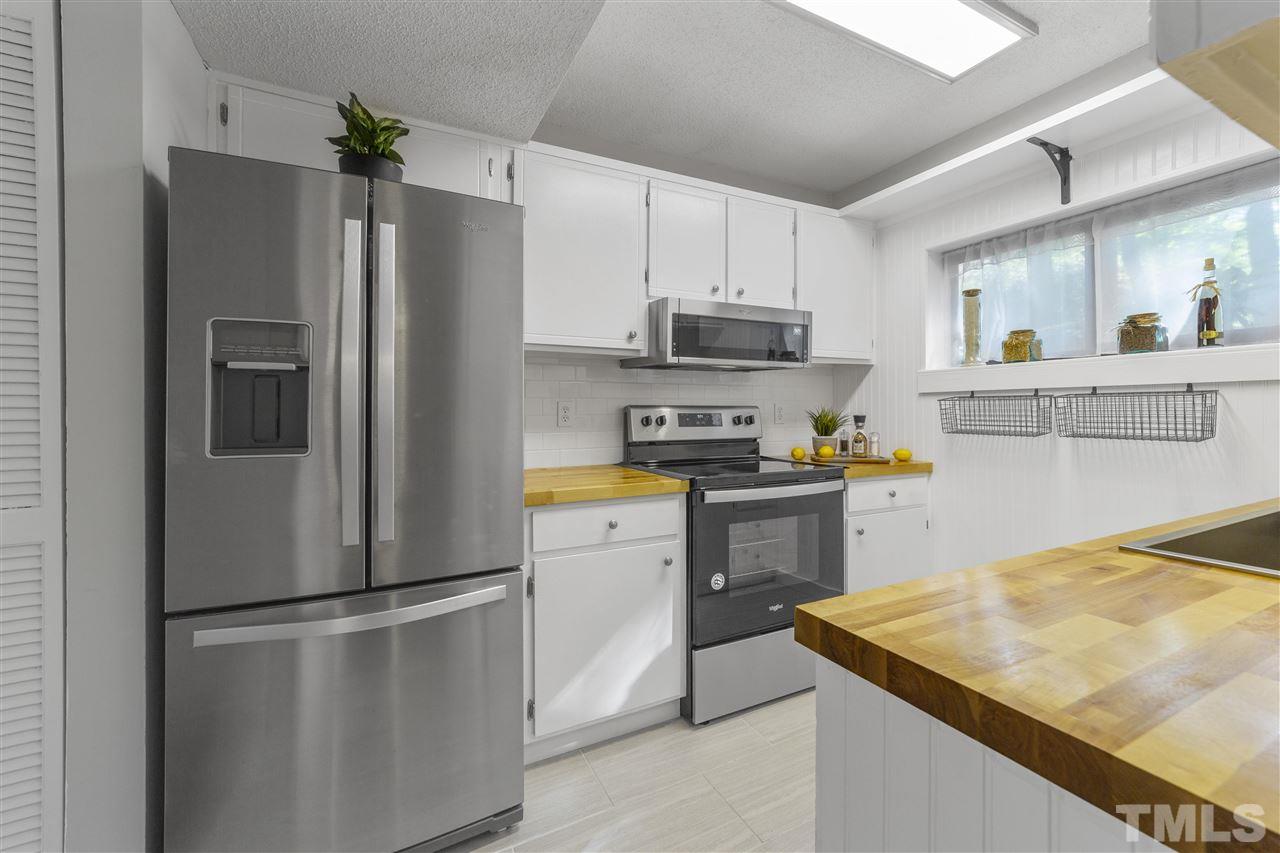 726 Godwin Court Raleigh, NC 27606 - Photo 6 of 23 a kitchen with a refrigerator a stove a sink and white cabinets