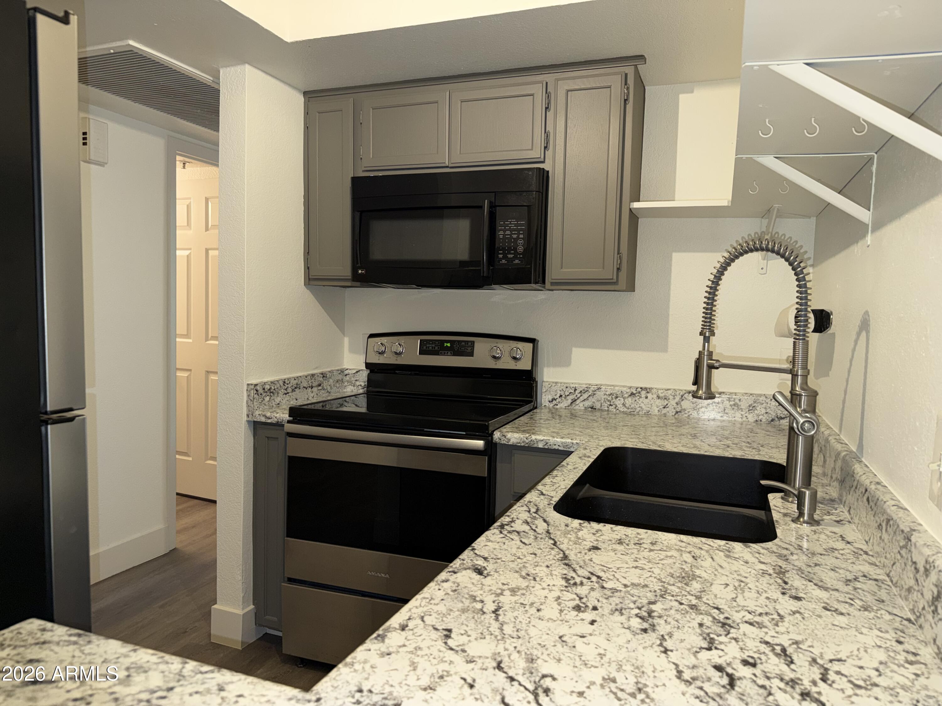 17 East Ruth Avenue, Unit 305 Phoenix, AZ 85020 - Photo 4 of 12 a kitchen with stainless steel appliances kitchen island granite countertop a stove and a sink