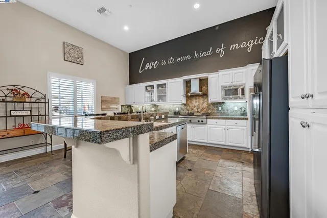 a kitchen with stainless steel appliances granite countertop a refrigerator and a stove top oven