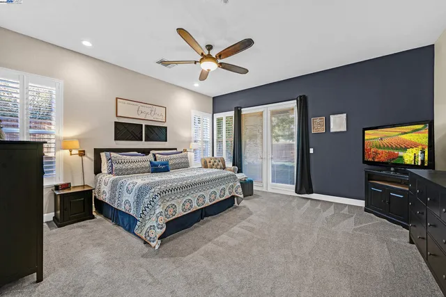 a spacious bedroom with a bed and a flat screen tv