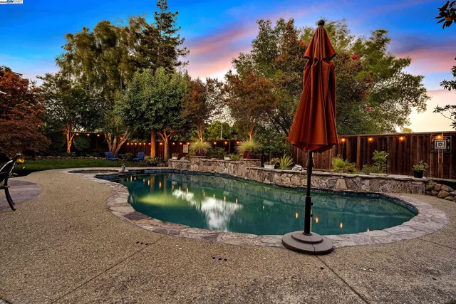 a view of a swimming pool with a patio and a yard