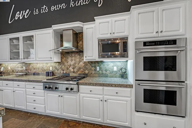 a kitchen with granite countertop white cabinets stainless steel appliances and sink