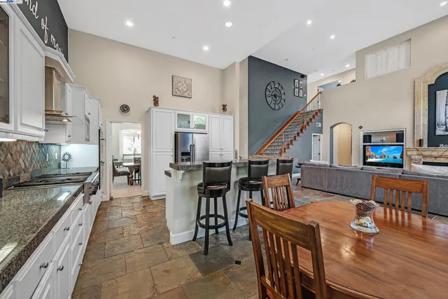 a kitchen with stainless steel appliances granite countertop a refrigerator a stove and a dining table with wooden floor