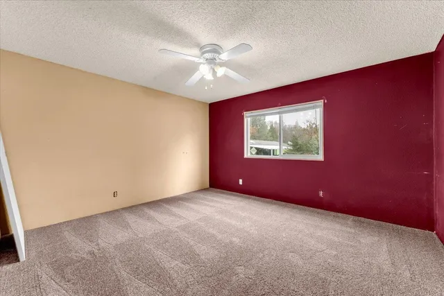 an empty room with window and ceiling fan