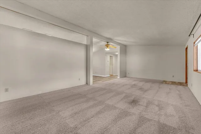 a view of an empty room with window and chandelier fan
