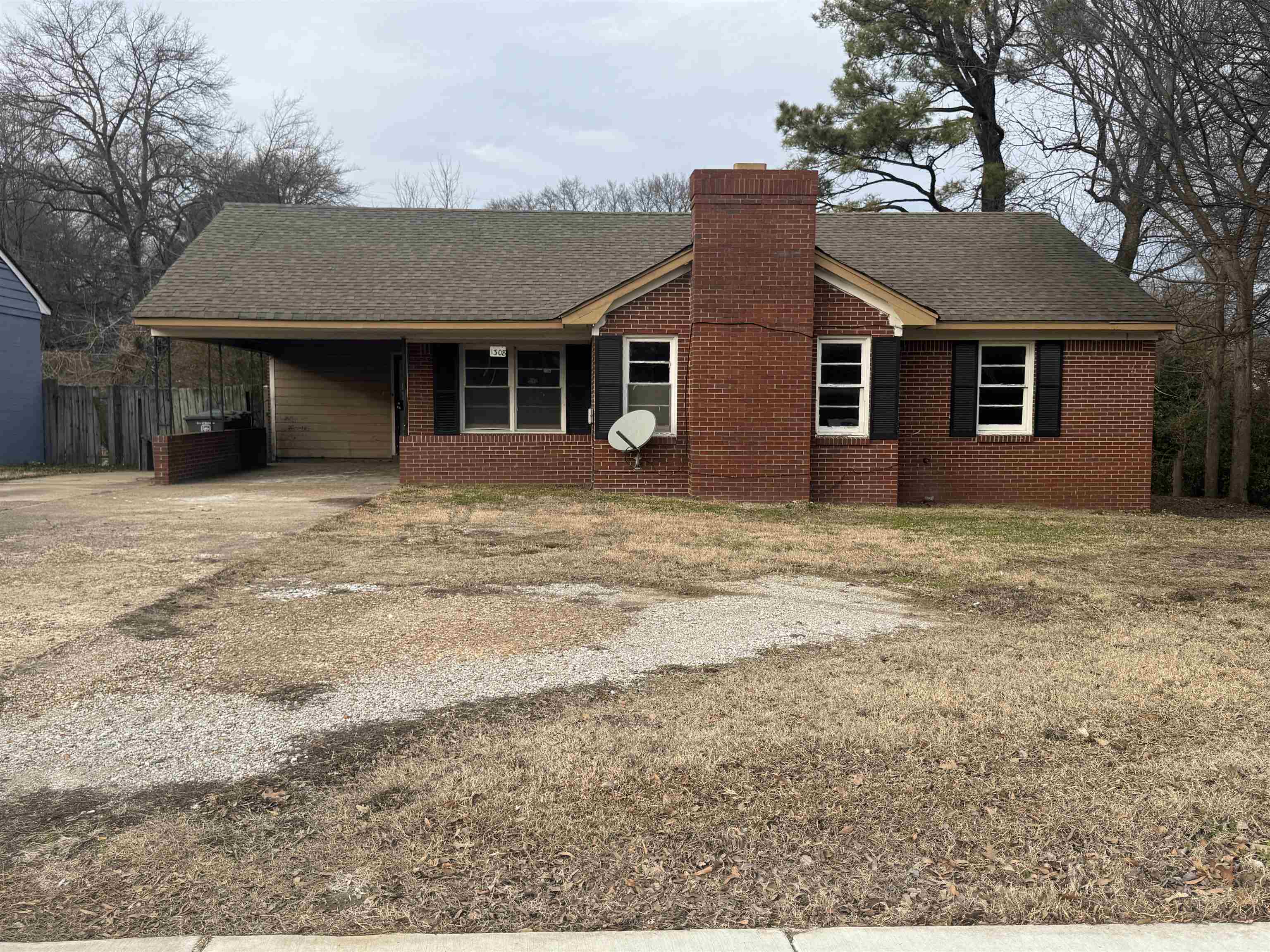 View of front of house featuring a shingled roof, a chimney, a carport, and concrete driveway