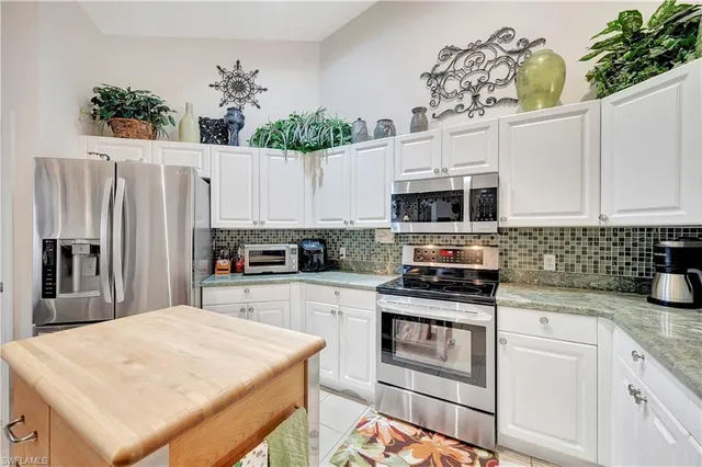 a kitchen with stainless steel appliances kitchen island granite countertop a refrigerator and a stove top oven