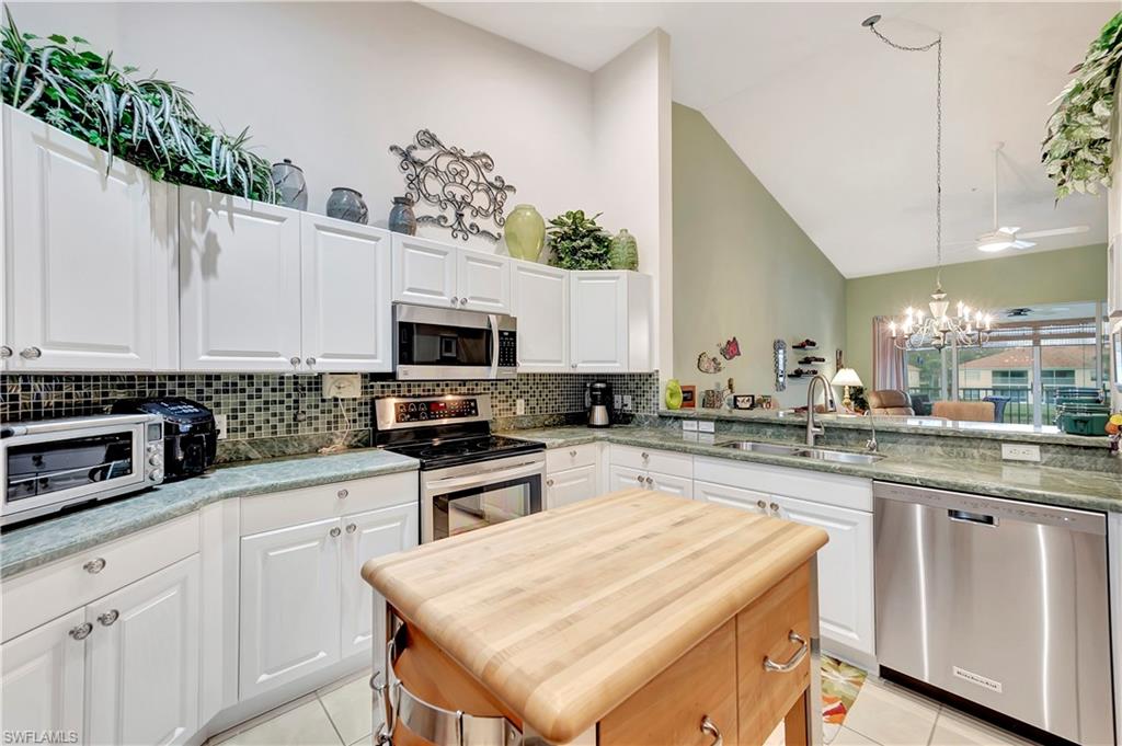 3055 Horizon Lane, Unit 1706 Naples, FL 34109 - Photo 7 of 42 a kitchen with stainless steel appliances granite countertop a stove top oven a sink a microwave and a refrigerator