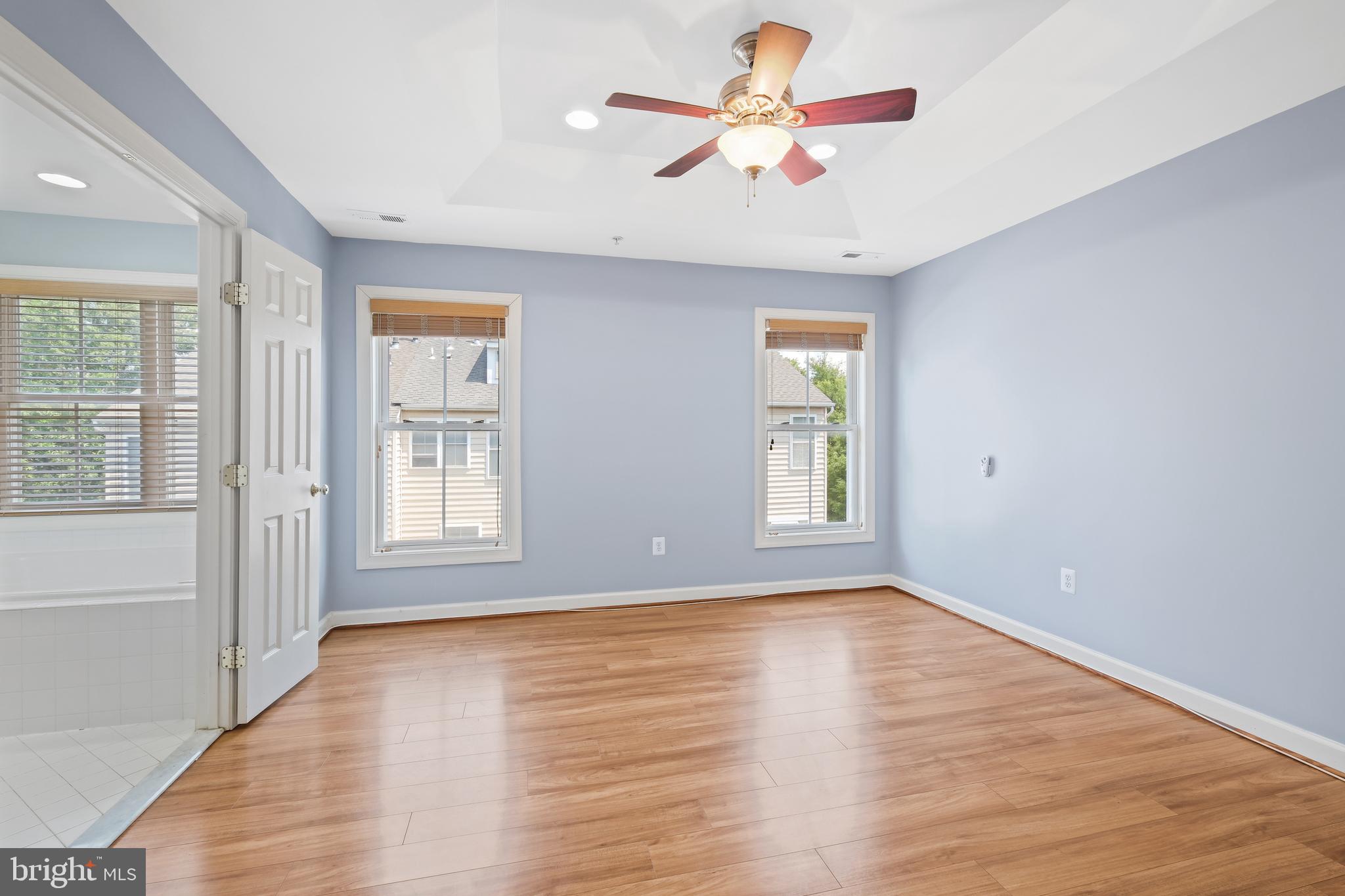 10728 Horde Street Silver Spring, MD 20902 - Photo 16 of 38 an empty room with wooden floor chandelier fan and windows