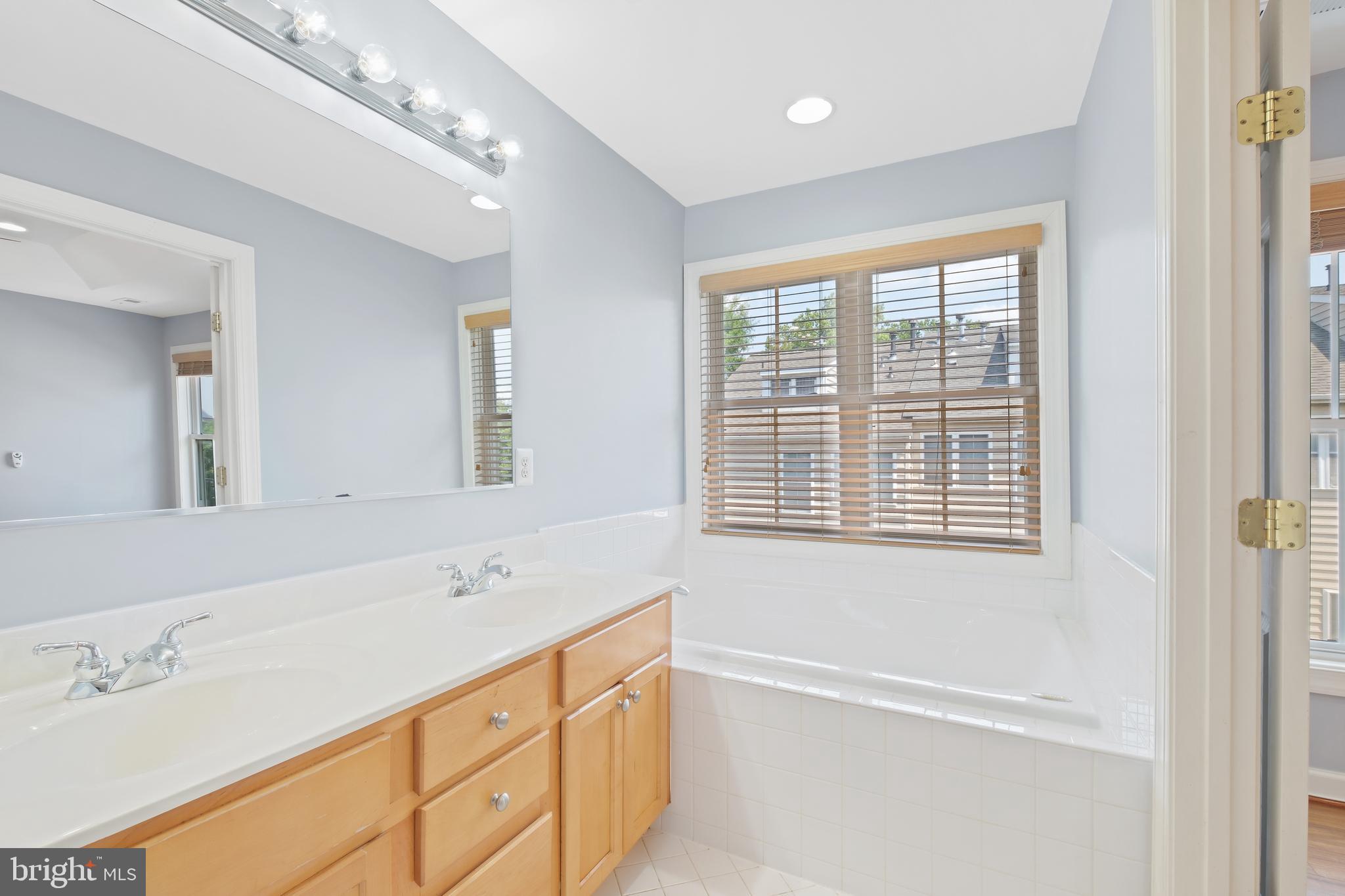 10728 Horde Street Silver Spring, MD 20902 - Photo 21 of 38 a spacious bathroom with double vanity a mirror a double vanity a window and a shower