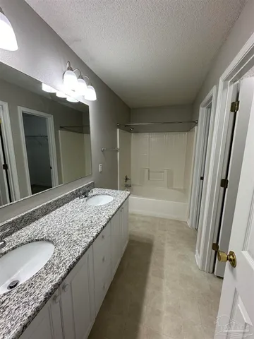 a bathroom with a granite countertop sink a mirror and a bathtub
