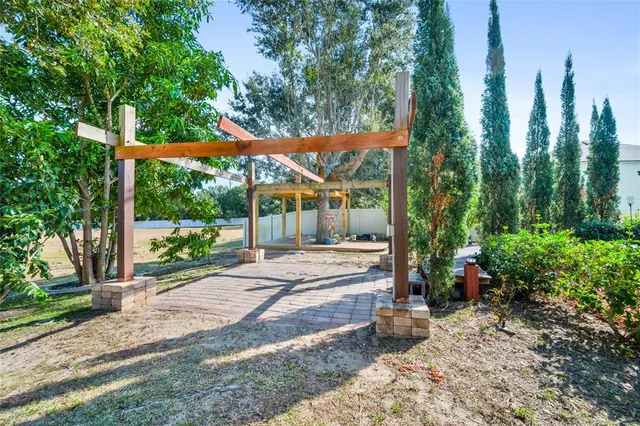 a view of a patio with table and chairs potted plants and large tree